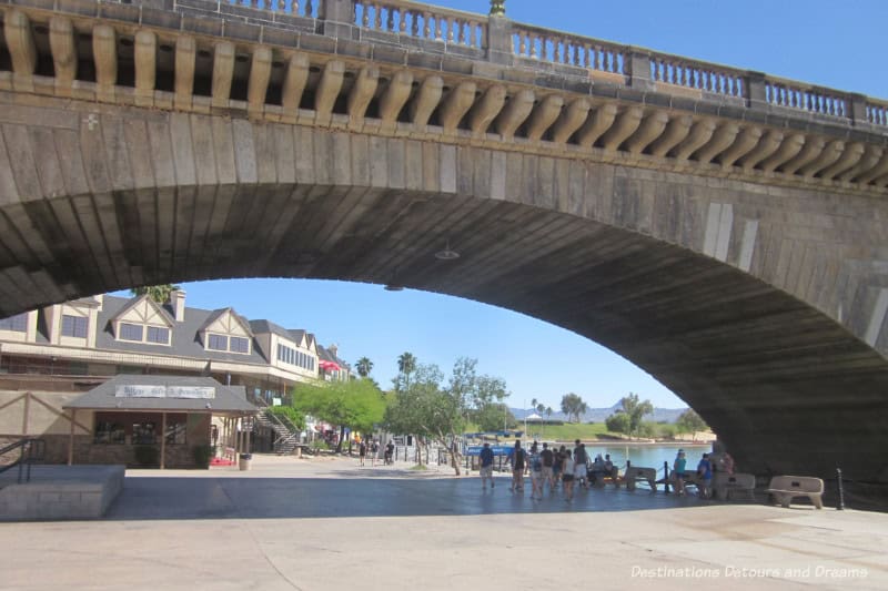 Walkway underneath a stone bridge with mock village