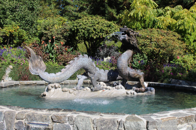 Fountain with dragon sculptures amid garden plants