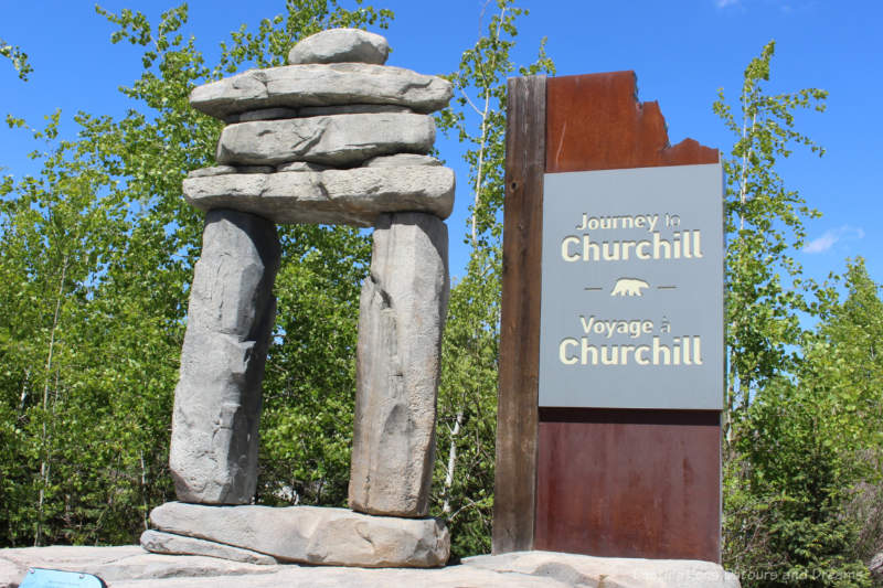 Large Inukshuk with sign beside it reading Journey to Churchill