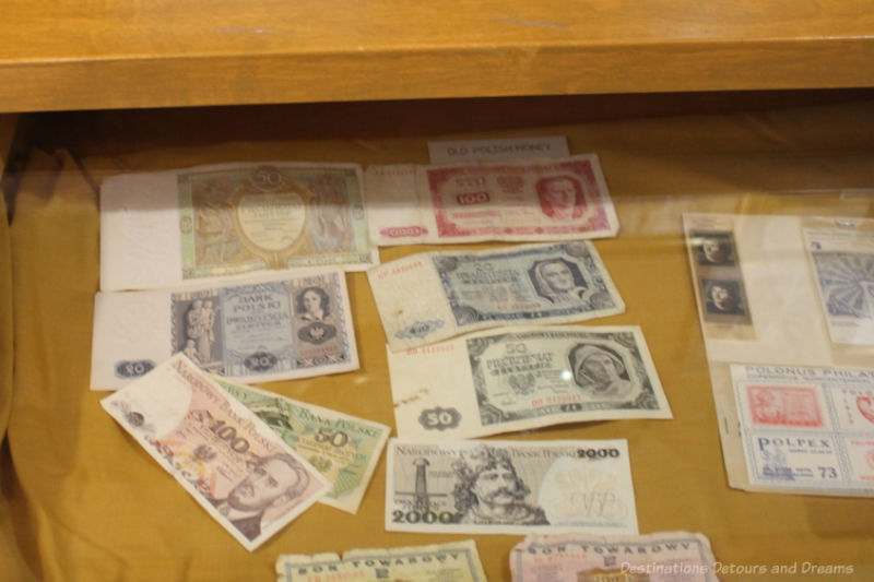 A collection of Polish currency and stamps in a glass-topped display cabinet in a museum