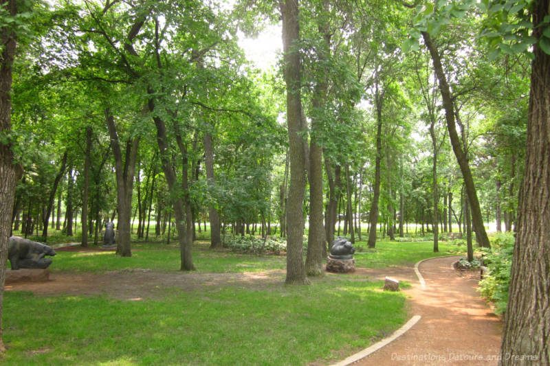 Pathway through treed area with sculptures scattered throughout