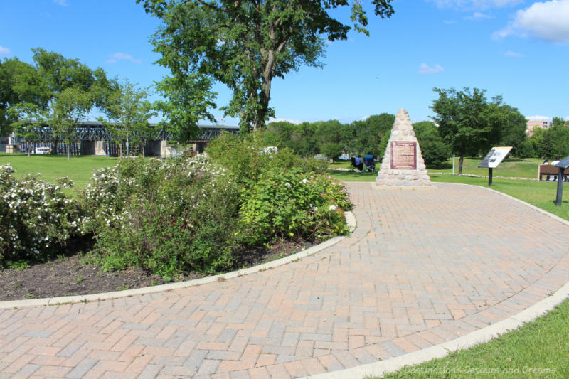 Garden, path around it, and stone monument commemorating 100th anniversary of St. Andrews Lock and Dam