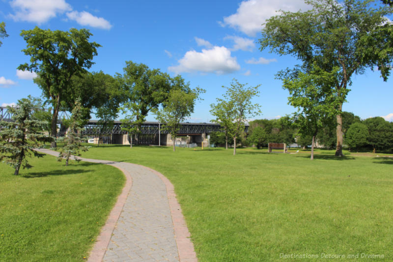 Green space along river with view of bridge with dam and lock in background