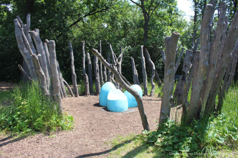 Three blue balls (for climbing?) in a circle fenced by dead tree limbs