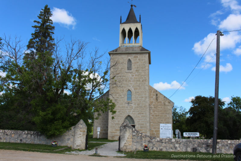 Old stone church with central tower in a church yard bordered with a stone fence