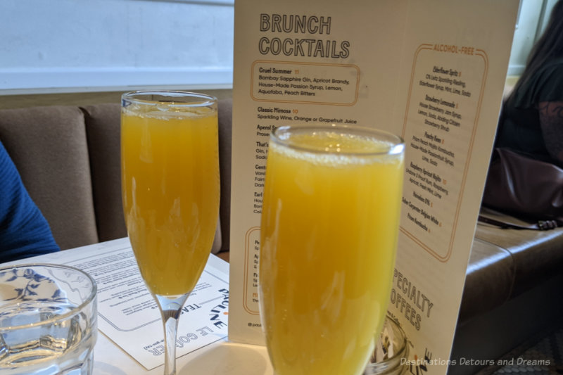 Two glasses of Mimosas in front of a brunch cocktail menu