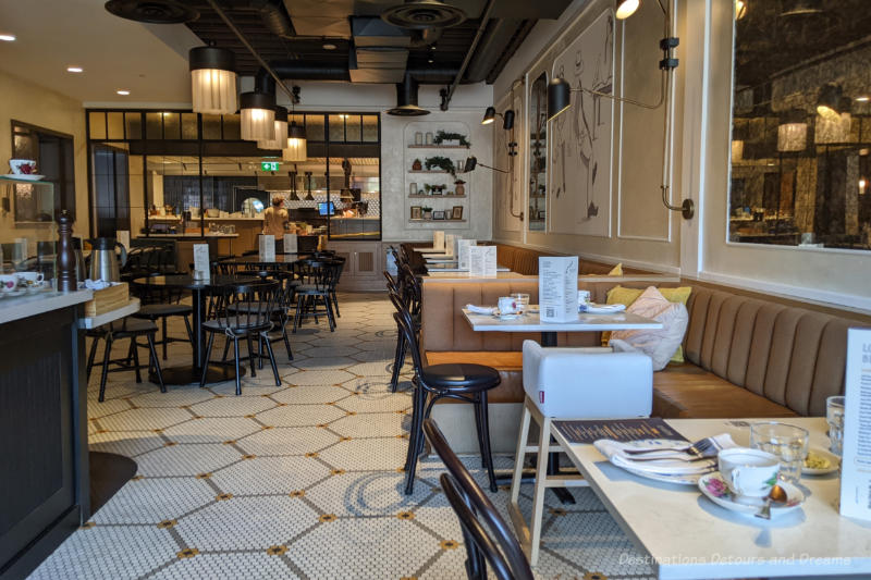 Interior of a bistro with tiled floor, dark wood tables and chairs, white walls with whimsical drawings