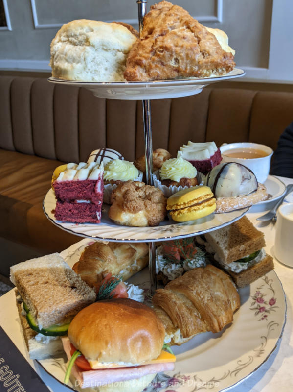 Three tiered china tray containing scones, sandwiches, and sweets of French afternoon tea