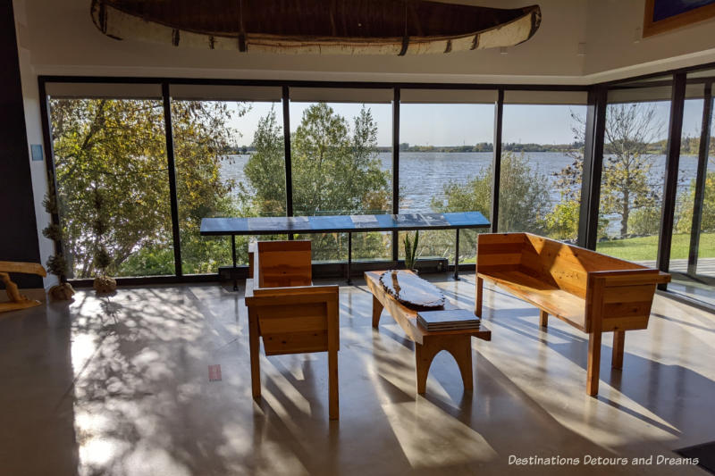 Benches in a lobby area of museum with a wall of windows offering view of river behind the museum