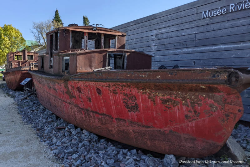 Weathered and worn old tugboat in front of a museum