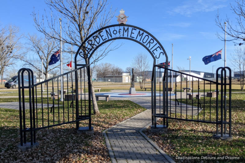 Black metal fence and arched gate with name Garden of Memories leading into a circular memorial area