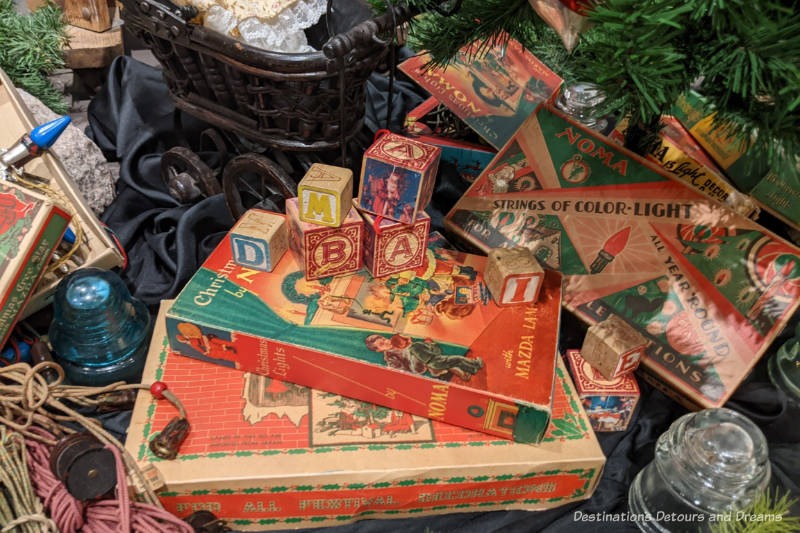 A collection of Christmas lights and toy blocks under a Christmas tree