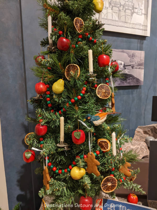 Christmas tree decorated with candles, gingerbread men, apple ornaments, and dried orange slices