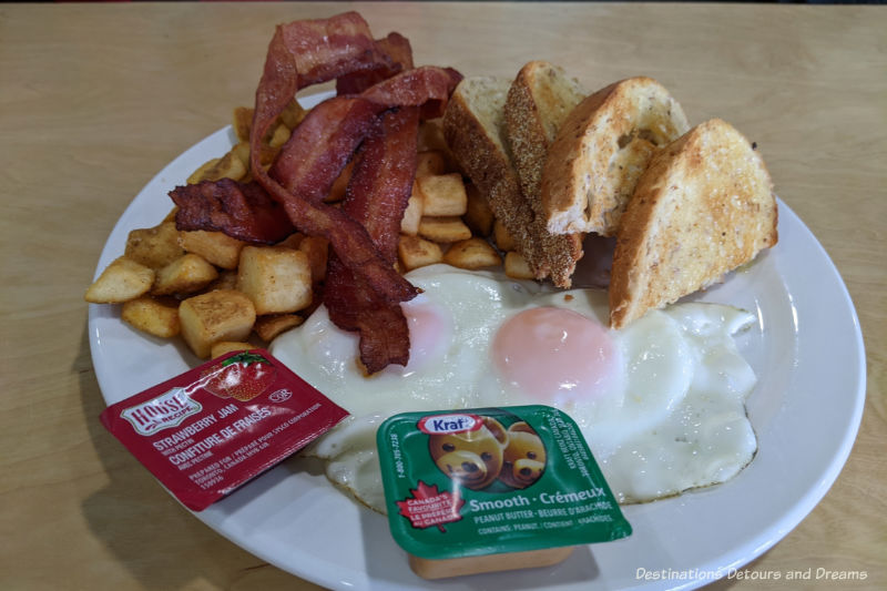 Plate of two poached eggs, bacon, toast, and breakfast potatoes