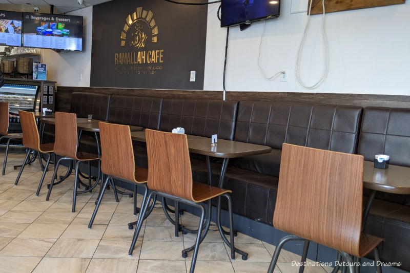 Plain interior of a restaurant with bench seating along wall and simple dark brown tables and light brown wood veneer chairs