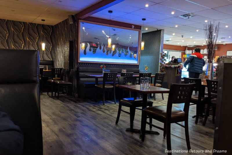 Interior of a restaurant with dark wood floor and dark brown tables and chairs