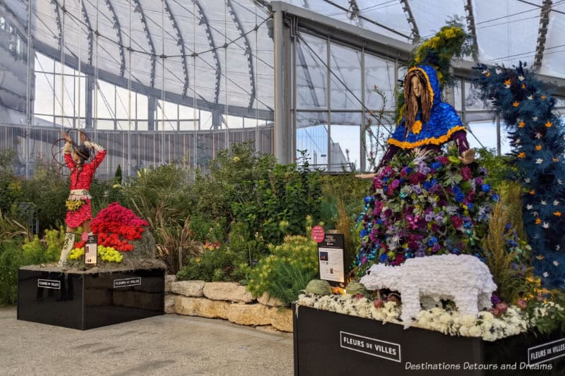 A couple of floral art displays on mannequins inside an indoor garden