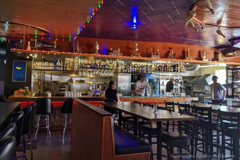 Tables in a restaurant/lounge area with the bar/kitchen area along the back wall