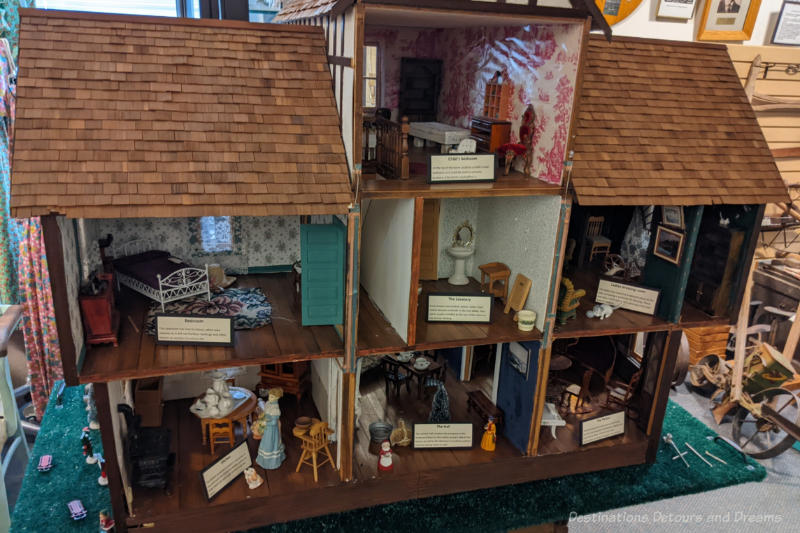 A large dollhouse with rooms furnished to reflect past times